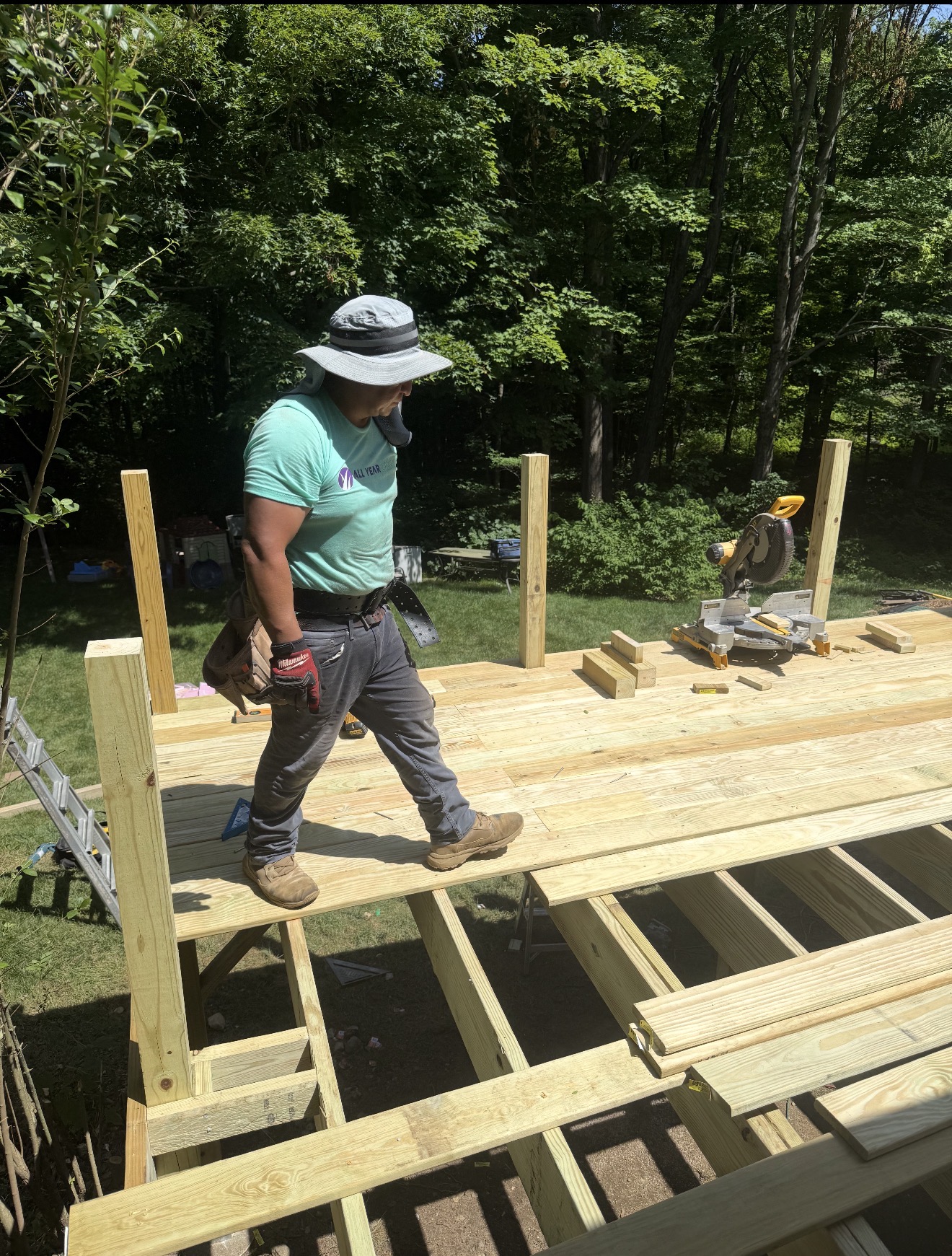 All Year Design & Build crew member walking new deck boards over framed joists in Prospect, CT