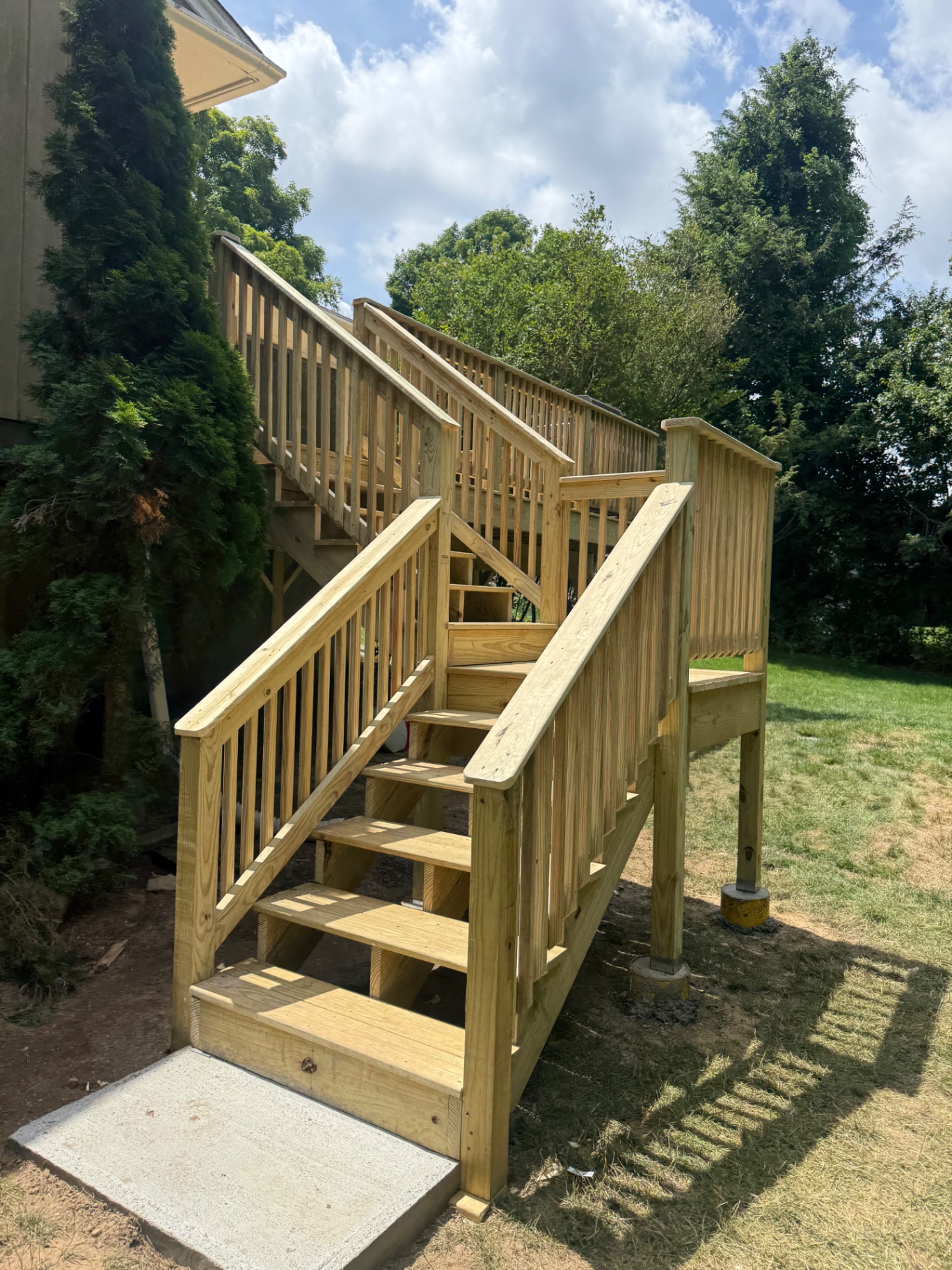 Completed pressure-treated deck stairs with railings landing on a concrete pad in Prospect, CT